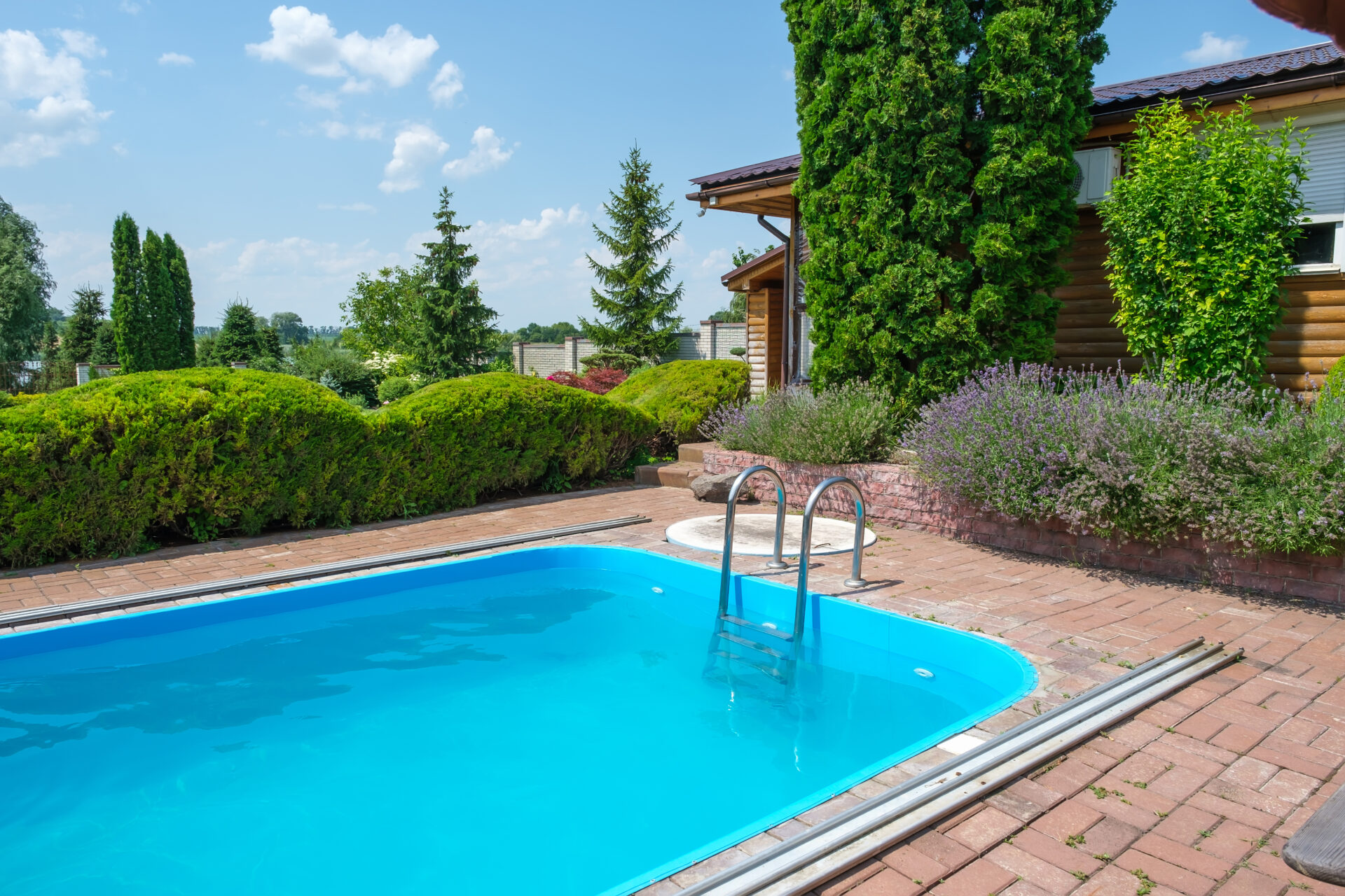 Swimming pool and garden with nicely trimmed bushes and stones in backyard. Landscape design. High quality photo